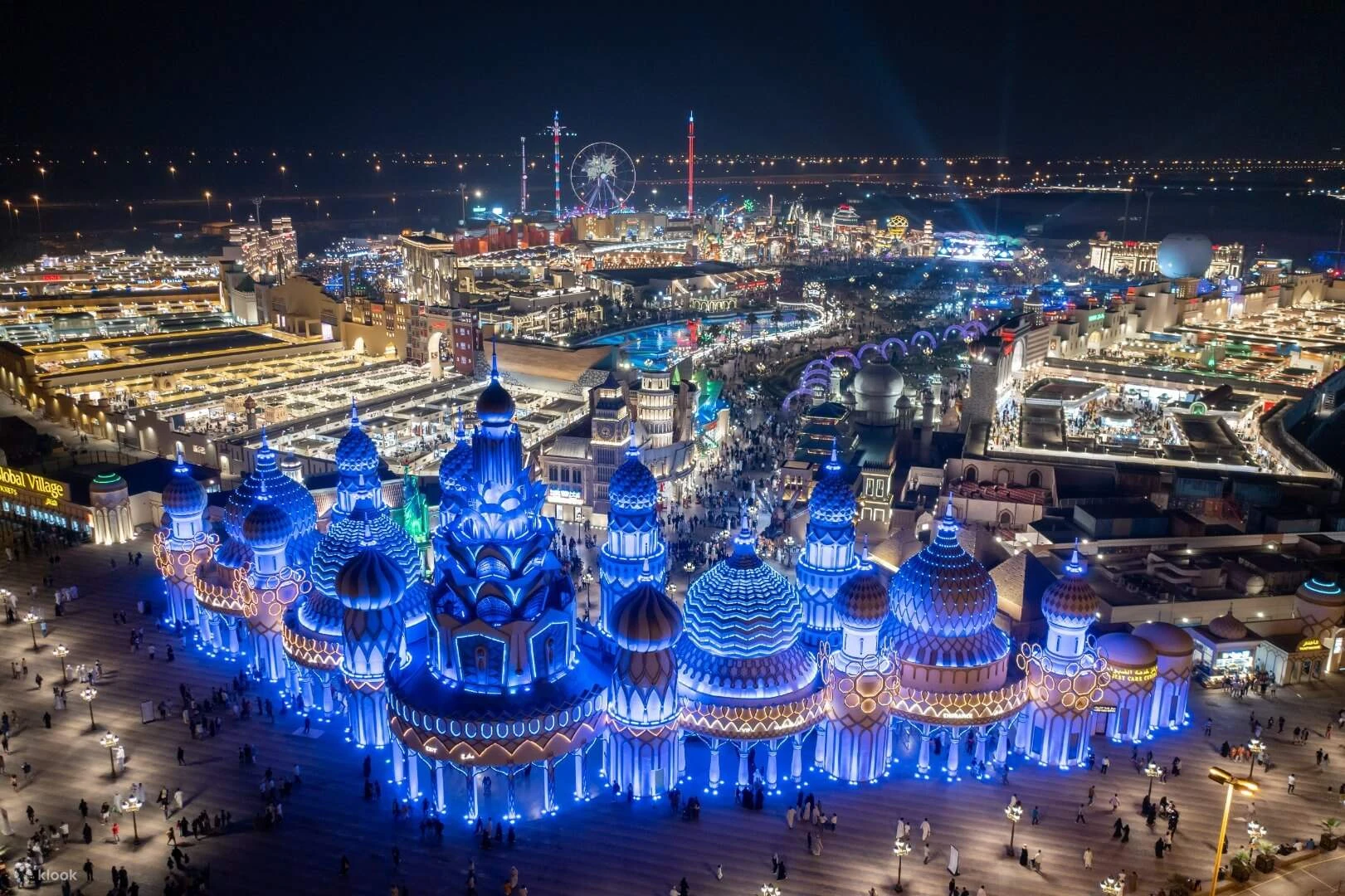Illuminated themed pavilions and crowds at Global Village, Dubai, photographed at night